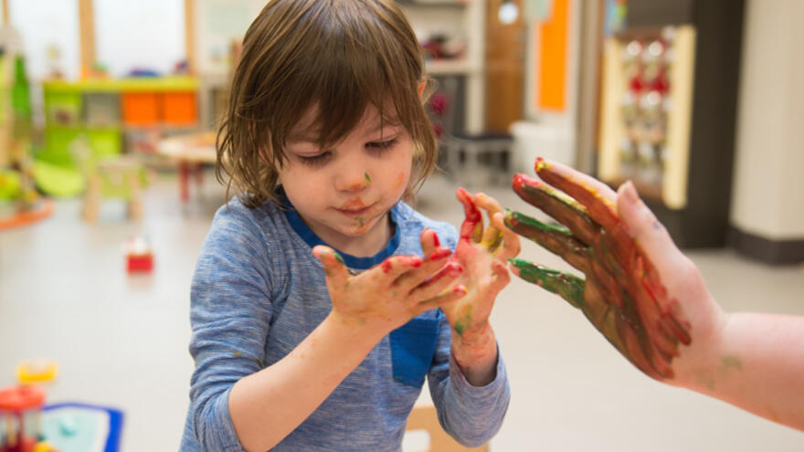 Young boy playing with paints in nursery