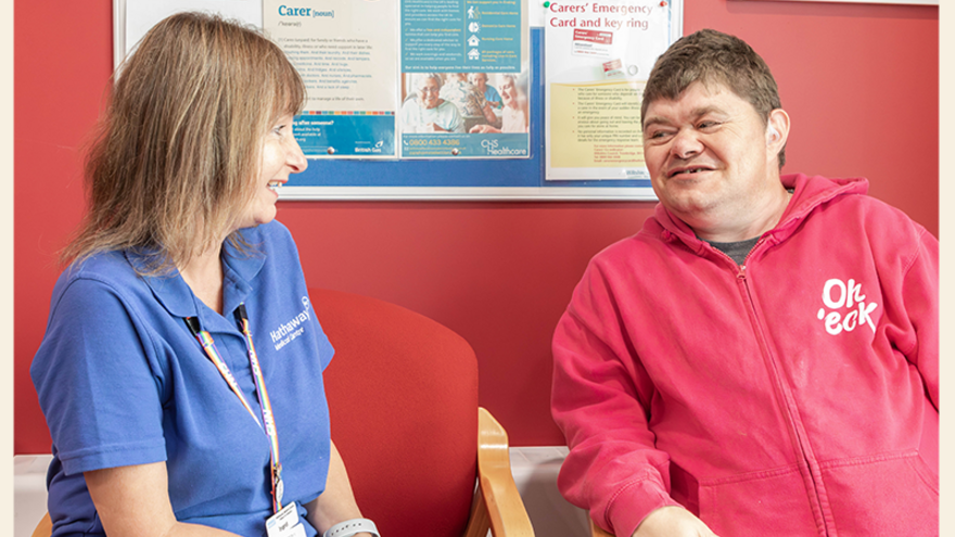 A nurse talks to a man with learning disabilities in a doctors waiting room