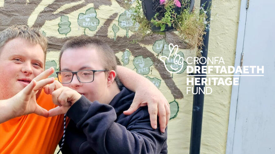 Two men with down's syndrome making a heart shape with their hands.