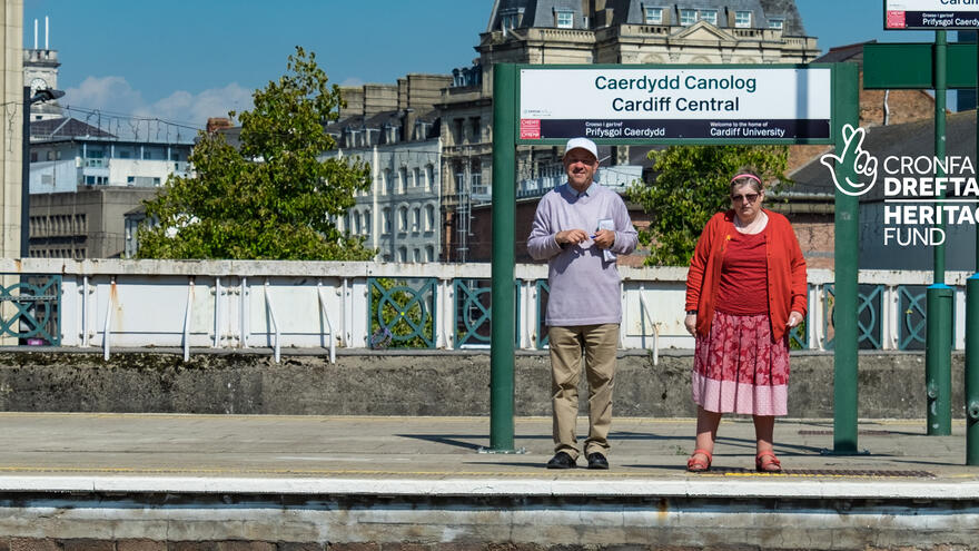 Two friends standing on Cardiff Queen Street Railway Station waiting for a train