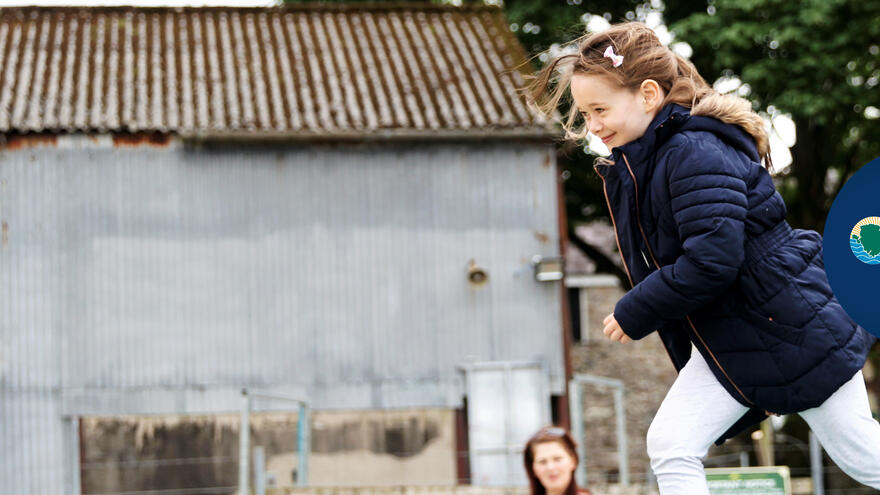 A young girl runs in an accessible play park.