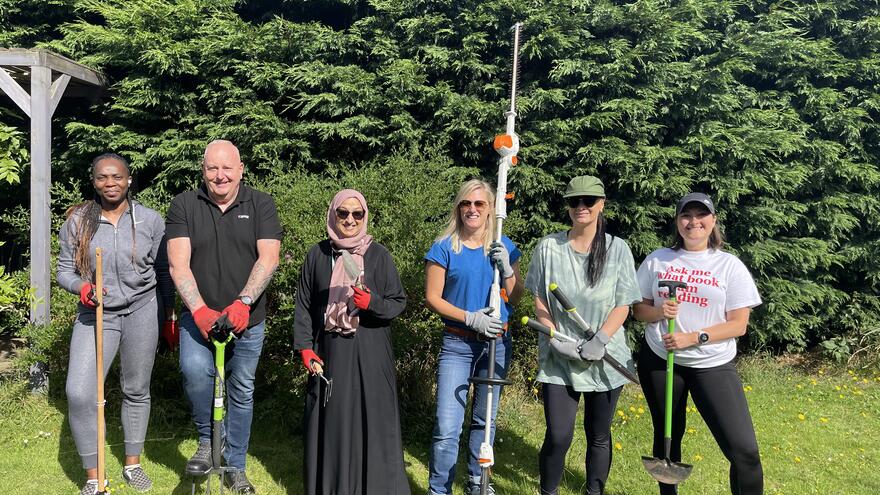 people standing in a row with gardening tools corporate volunteers
