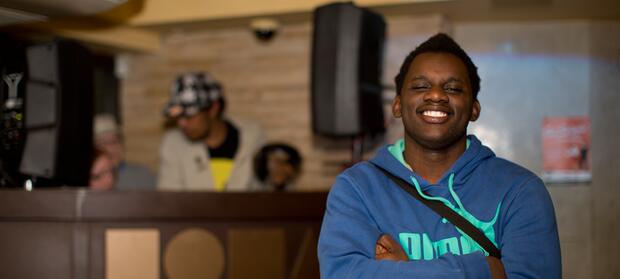 Young man stood inside smiling with his arms folded