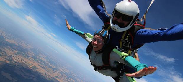 Two people strapped together doing a skydive.