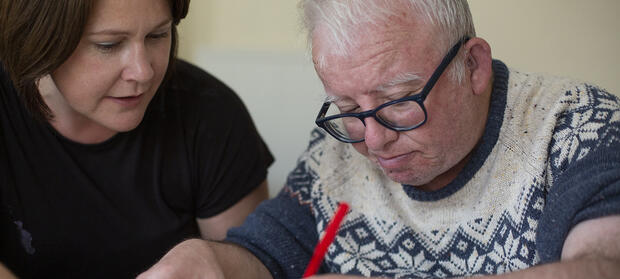 Woman and man sat together at table drawing with coloured pens